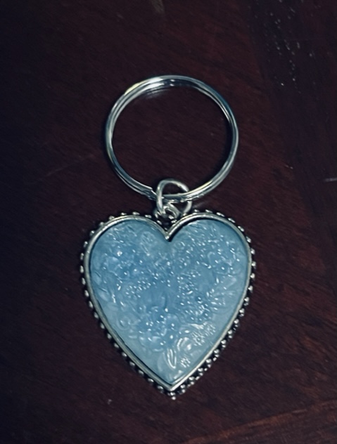 Shimmery pale blue heart charm with silver detailing on the edges.