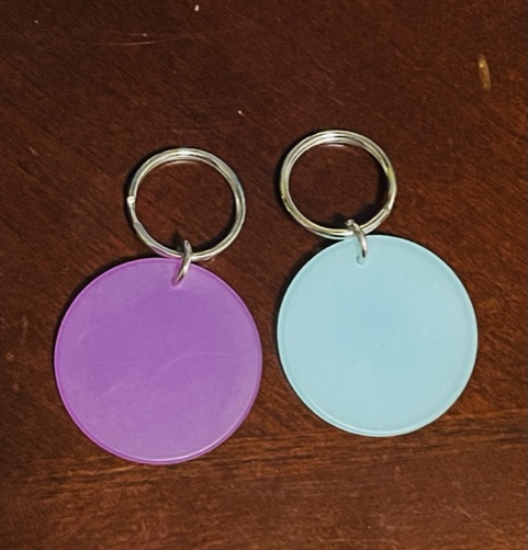 Small, solid circle of blue or purple color hanging from a silver ring. 