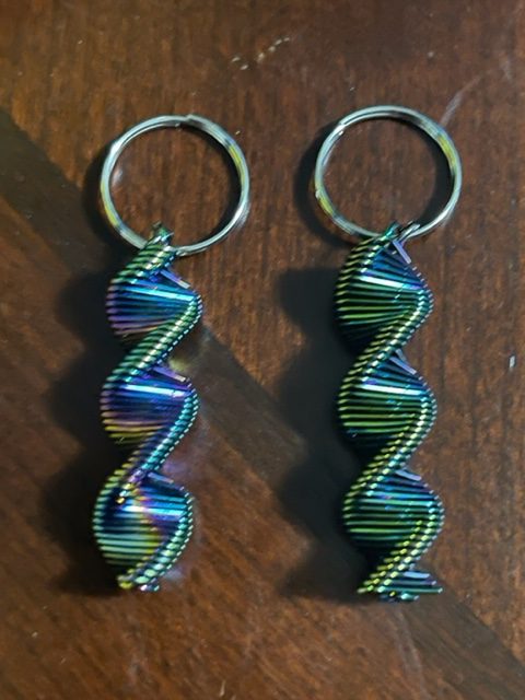 Two multi-colored (green, purple, and blue) swivel bangles charms laying against a wooden surface.