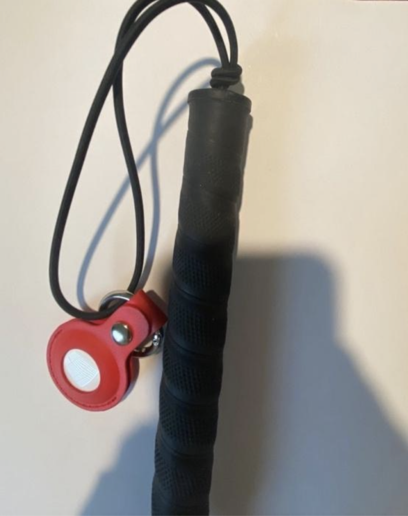 red leather apple air tag holster hanging from the wrist strap of a cane
