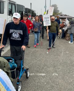 A group of people with canes and guide dogs exiting the parking lot to begin their march on White Cane Day.