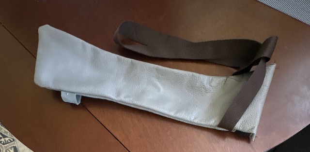 an example of the leather cane pouch. this pouch is grey, empty, and laying on a table.