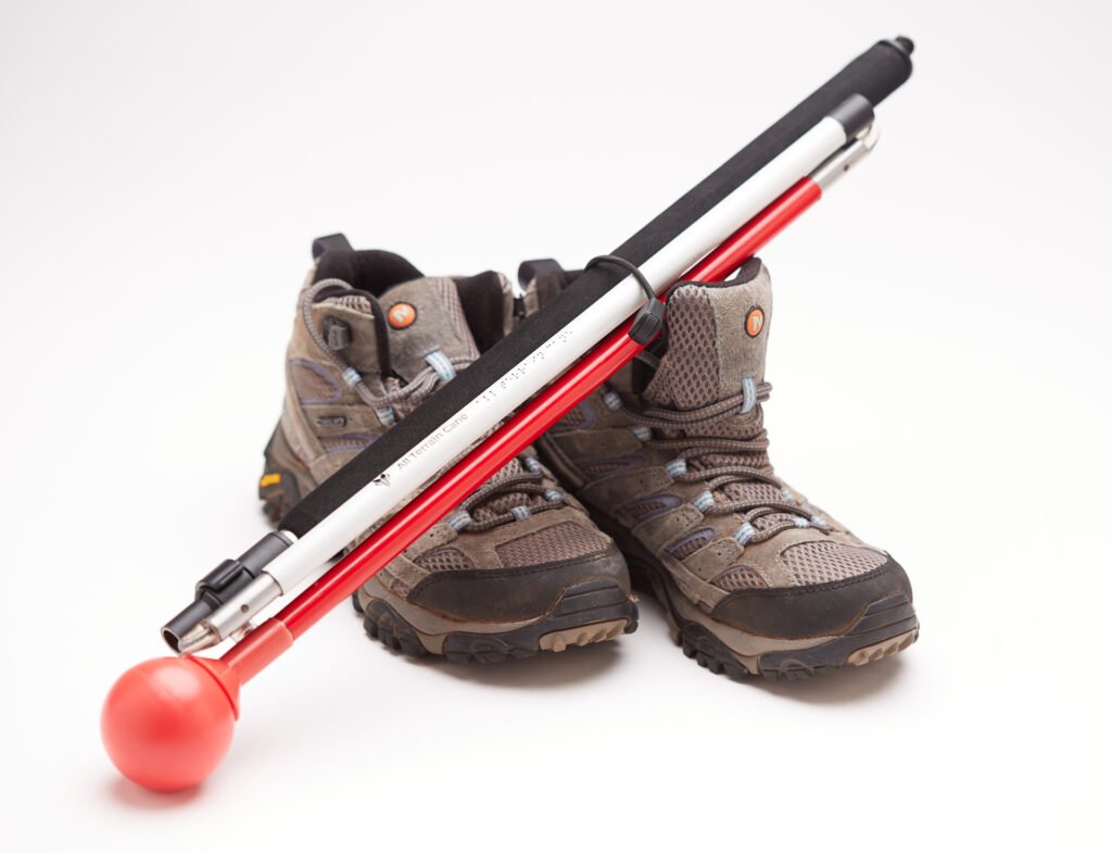 Folding All Terrain Cane propped up against hiking boots