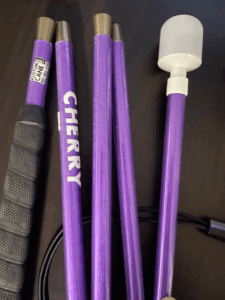 A vibrant purple cane with a shimmer finish, labeled "CHERRY" in bold white letters. It features a black grip and a white marshmallow-style tip, with a tag reading "Kustom Cane."