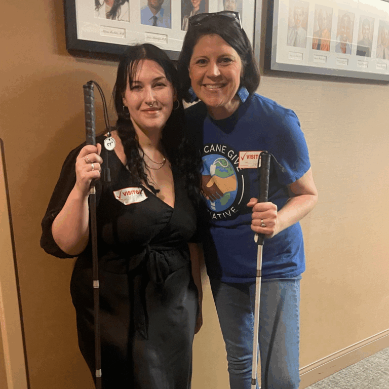Wendy standing and smiling with a cane recipient in a hallway