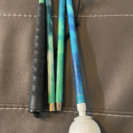 A beautifully designed mobility cane featuring a vibrant gradient inspired by the Northern Lights, with flowing shades of green, teal, and blue. It includes a black textured grip and a white rolling ball tip.