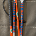 A cane wrapped in bright orange and blue designs with repeating "FLORIDA GATORS" text and Gators logos. It includes a black grip and a white rolling ball tip.