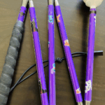 A playful purple cane featuring stickers of Disney characters including Stitch, Simba, and Maleficent. It has a black rubber grip and a white rolling ball tip.
