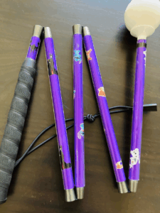 A playful purple cane featuring stickers of Disney characters including Stitch, Simba, and Maleficent. It has a black rubber grip and a white rolling ball tip.