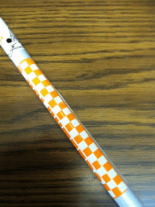 A cane with a white and orange checkerboard pattern, representing the University of Tennessee. It includes part of a Smokey (the dog) illustration near the top.
