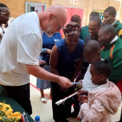 a you cane give volunteer hands out canes to children